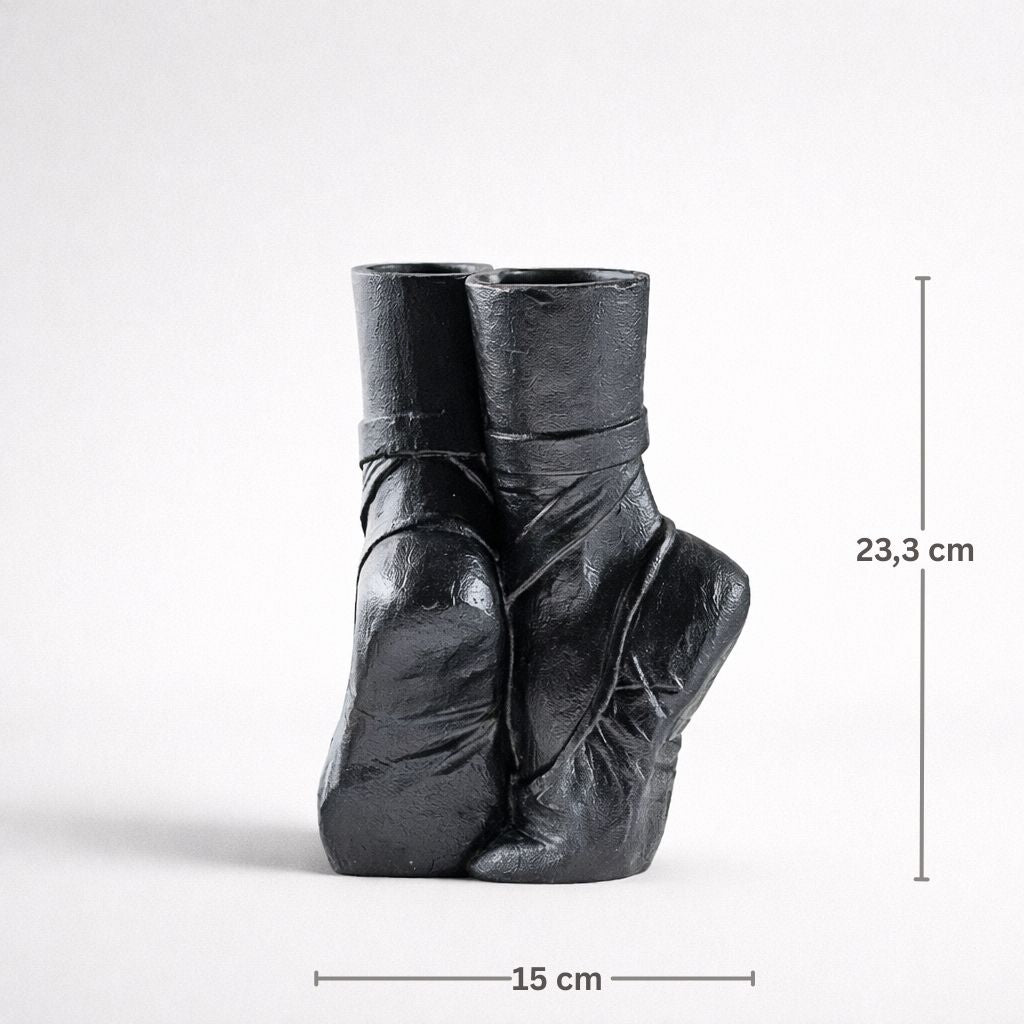Black ceramic vase shaped like a pair of feet with measurements on a white background