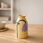 Yellow vase with purple and black design on a wooden table