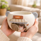 Cute ceramic cat cafe mug with 3D kitten design held in hands, Germiant aesthetic.