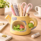 Cute yellow frog-themed pen holder with pens and scissors on a wooden desk, Germiant style