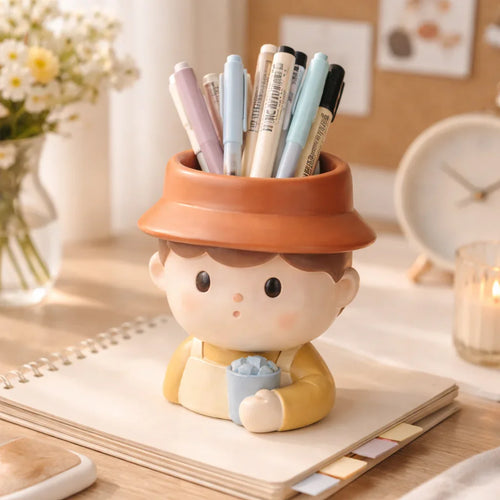 Cute boy-shaped ceramic pen holder with pens, on a desk with flowers and a notebook, Germiant