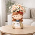 Decorative figurine of a girl with flowers on her head, holding a cat, on a wooden table.