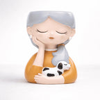 Decorative figurine of a woman with gray hair holding a dog on a white background