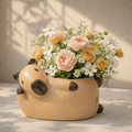 Floral arrangement in a capybara shaped pot on a neutral background