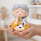 Person holding a decorative figurine of a woman with a dog on a blurred indoor background