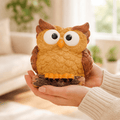Person holding a decorative owl figurine in a blurred indoor setting