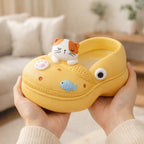 Yellow Germiant slipper with cute cat, fish, and paw decorations held indoors