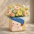 Floral arrangement in a cute, cartoon-like pot with a face on a neutral background