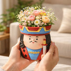 King-themed ceramic flower pot with pastel roses and small flowers held in hands